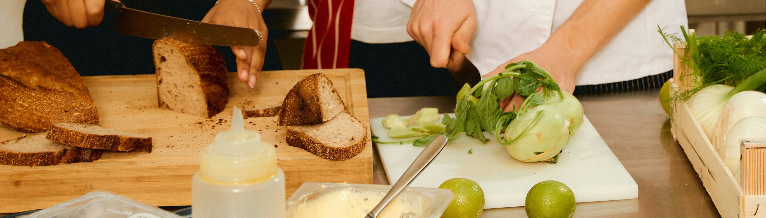 Chefs cutting bread and vegetables in a kitchen.