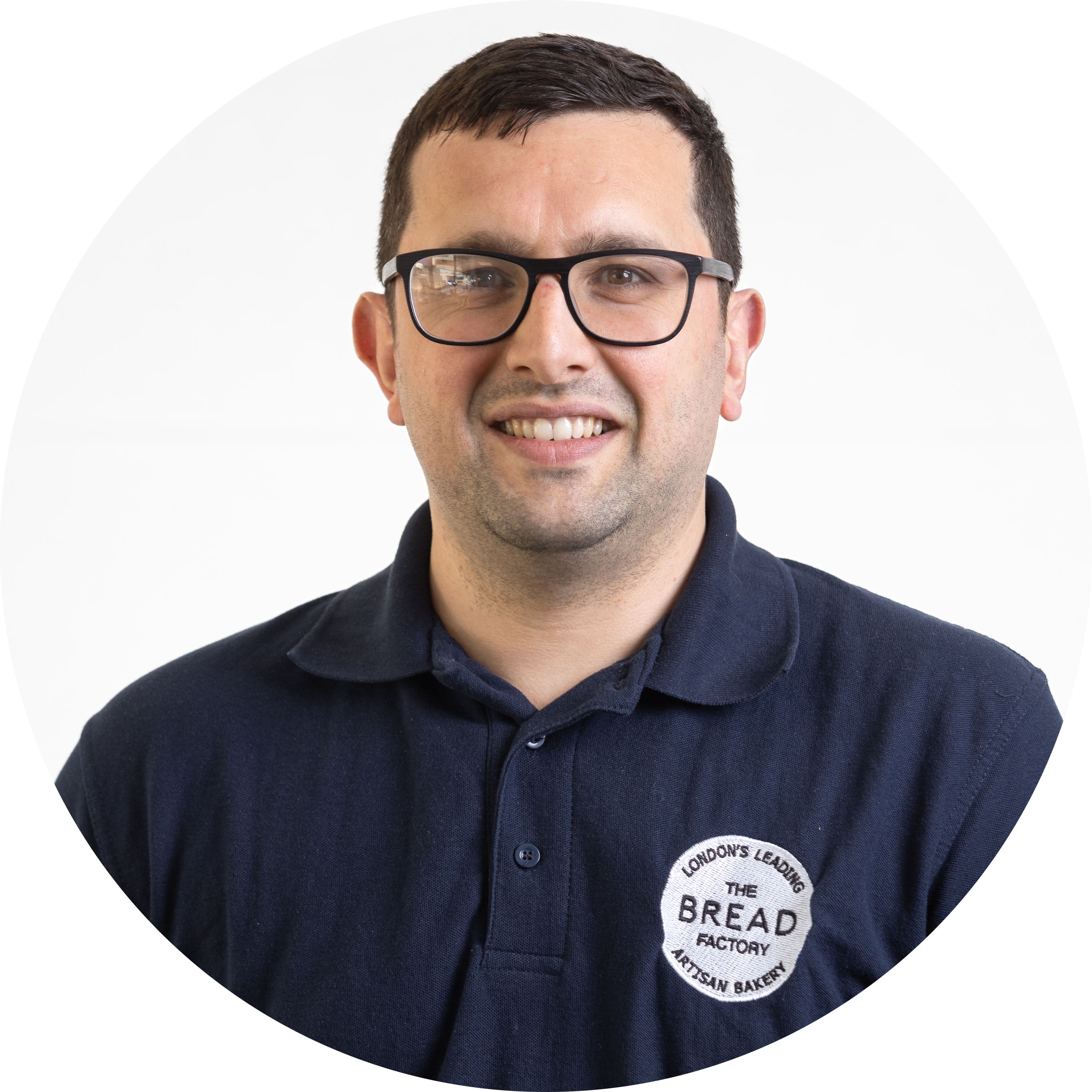 Man wearing glasses and a polo shirt with a bakery logo.
