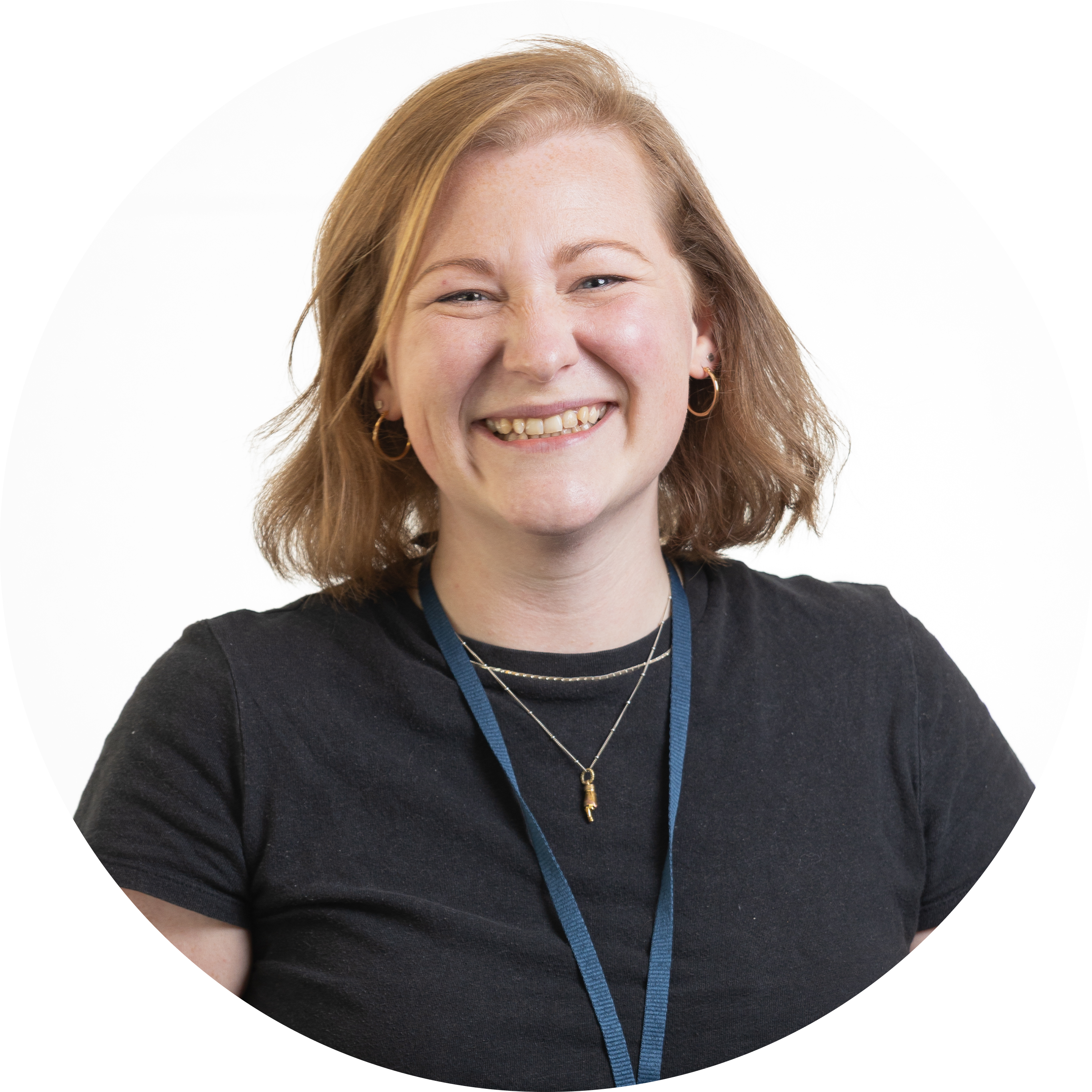 Woman with short hair, wearing a black shirt and a blue lanyard, smiling.