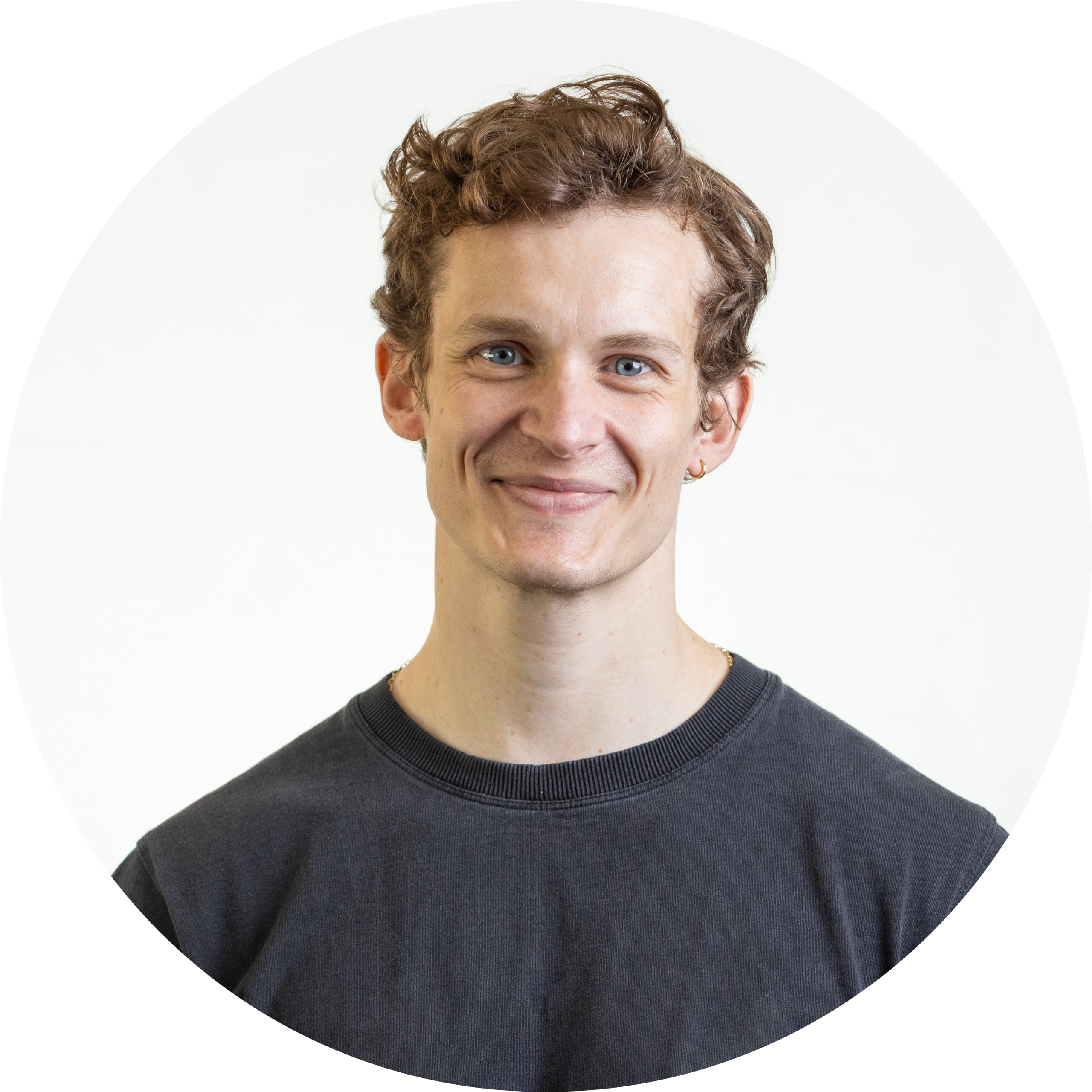 Smiling man with curly hair, wearing a dark shirt.