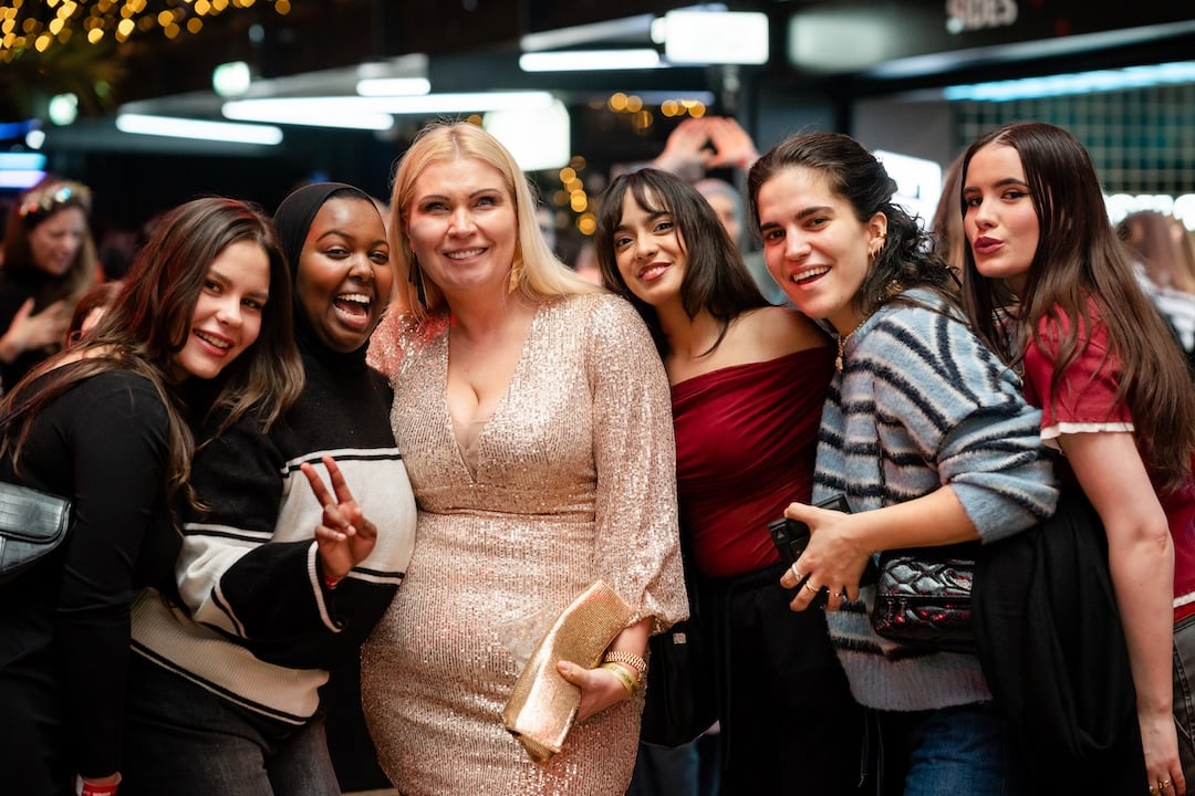 Women posing for a photo, smiling, and looking at the camera.