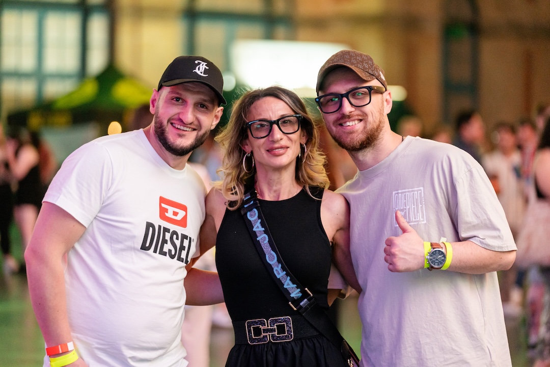 Three people smiling, posing for a photo. One gives a thumbs up.