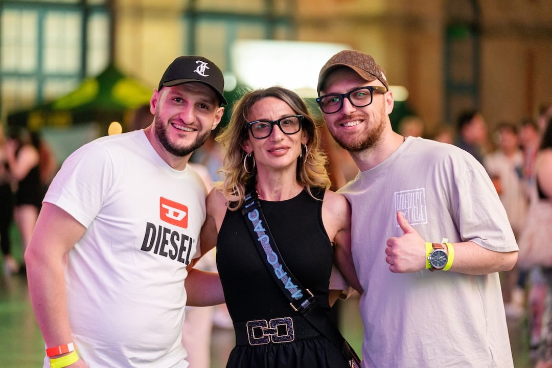 Three people smiling, posing for a photo. One gives a thumbs up.