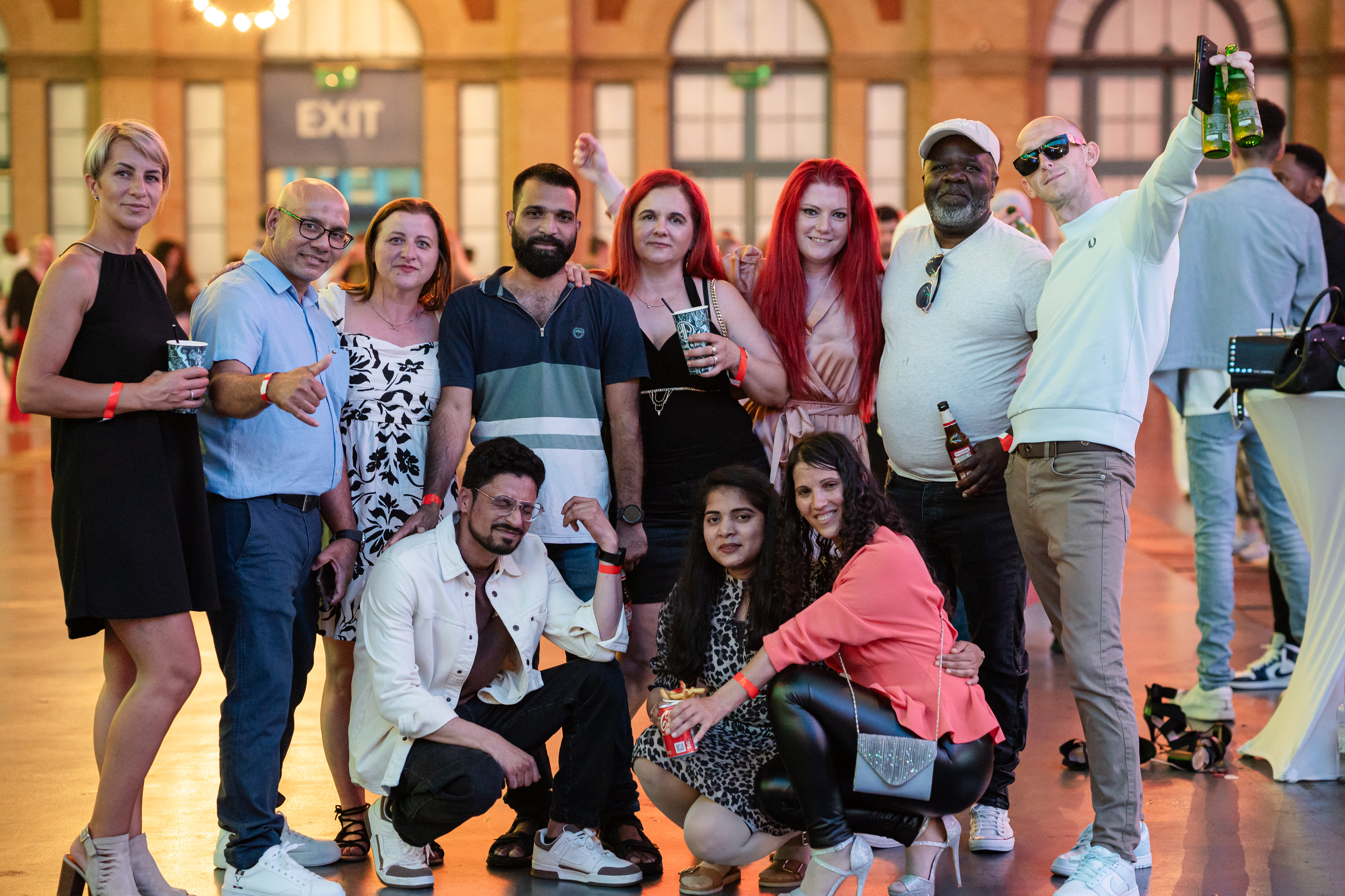 People posing for a photo, some holding drinks.